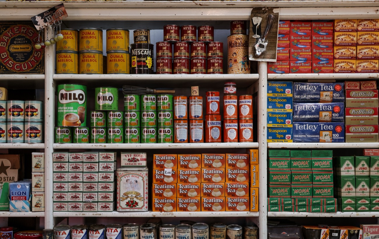 Stocked shelves of a South African general dealer — tea, coffee, biscuits and household staples.