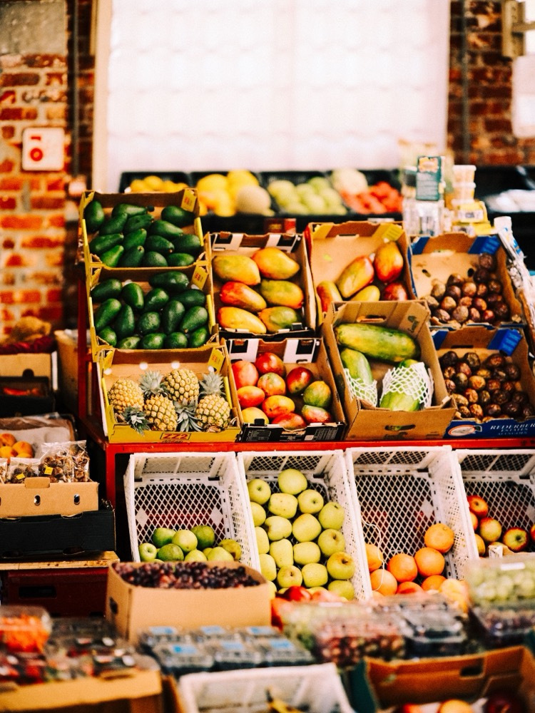 Crates of fresh produce stacked in a township shop — avocados, mangoes, pineapples and apples.